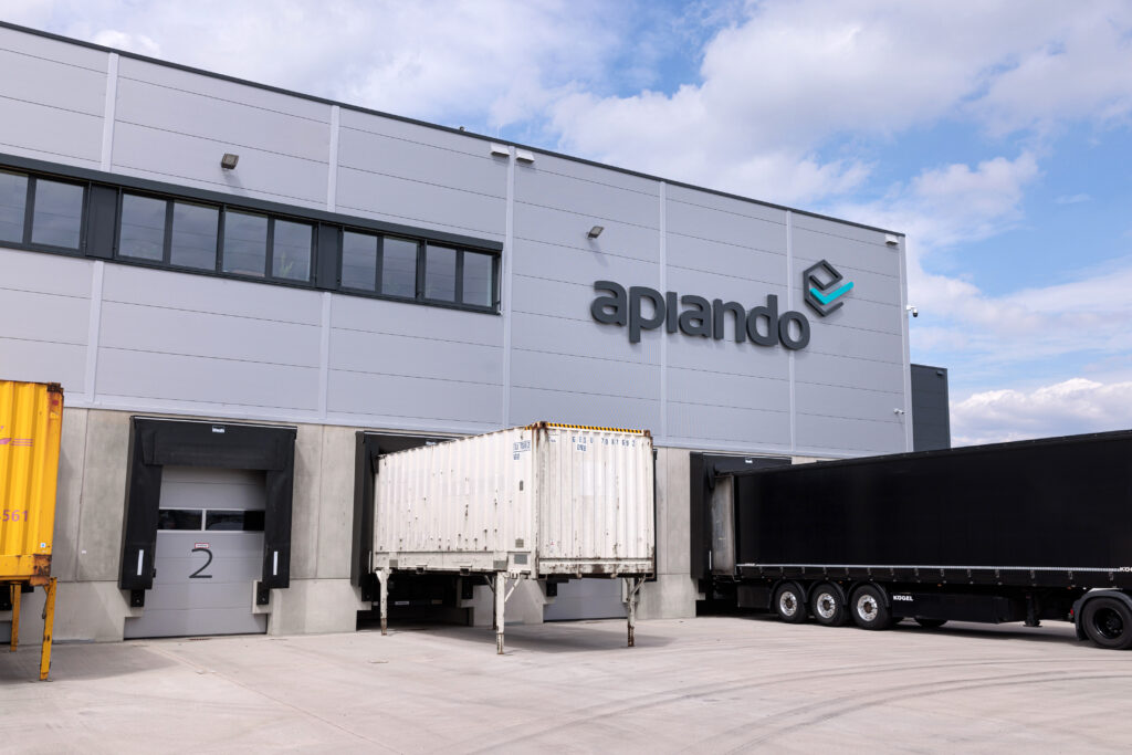 Exterior view of a modern fulfillment hall. Three lorries are being loaded